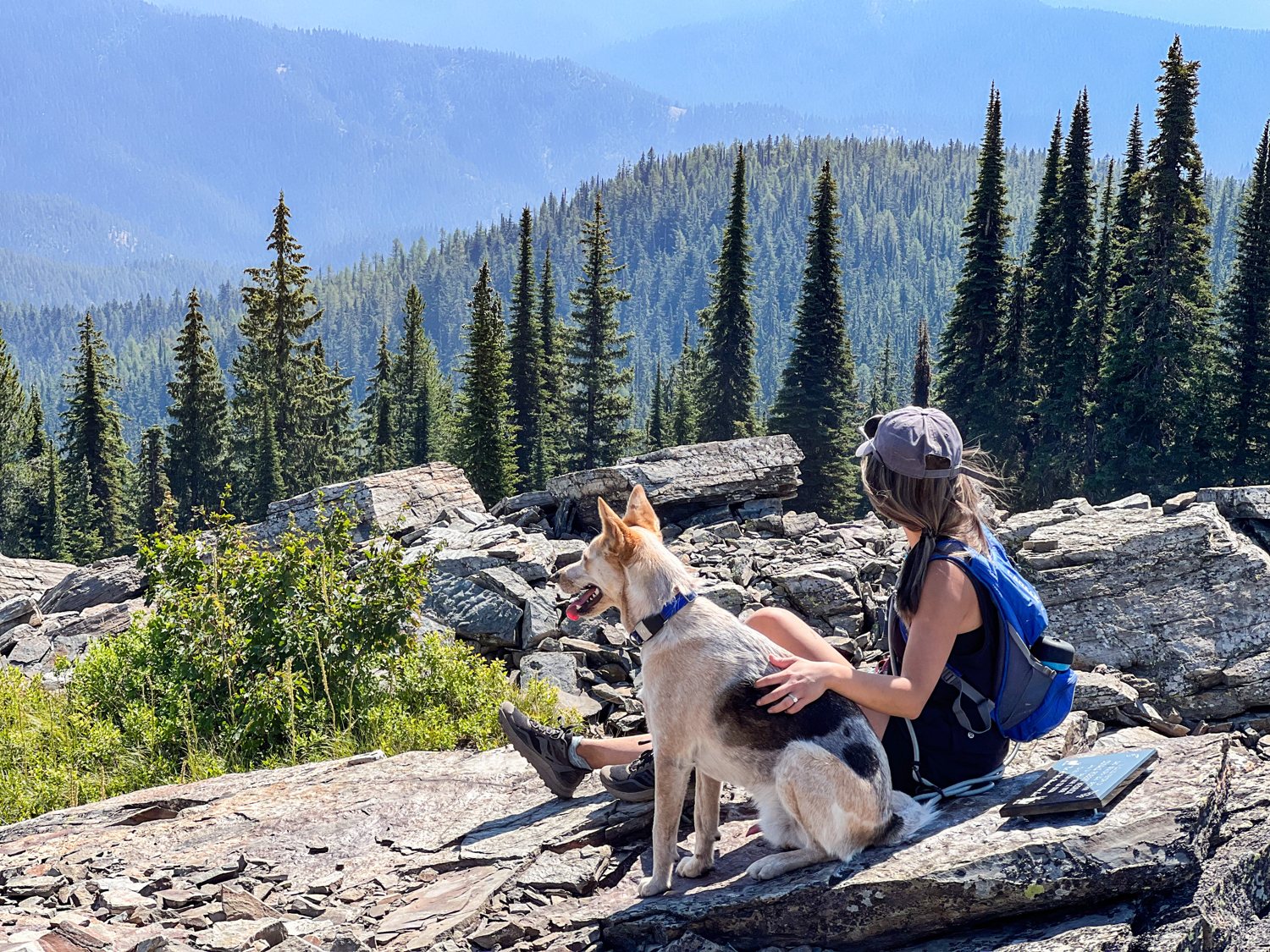 Diana and Toby resting together on a rocky summit above an alpine lake