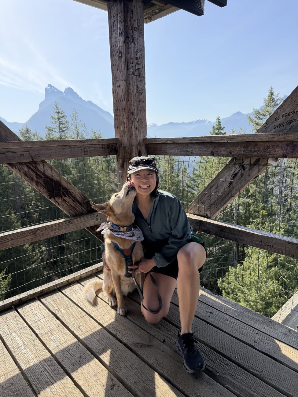 Diana and Toby resting at a mountain overlook with a sharp peak behind them